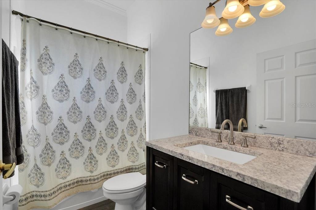 7601 226th Street East Bradenton, FL 34211 - Photo 30 of 50 a bathroom with a granite countertop sink toilet a mirror a vanity and shower