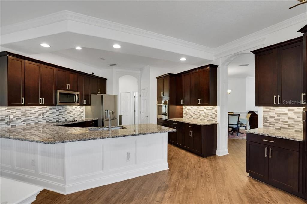 7601 226th Street East Bradenton, FL 34211 - Photo 7 of 50 a large kitchen with stainless steel appliances kitchen island granite countertop a large stove a sink dishwasher and white cabinets with wooden floor