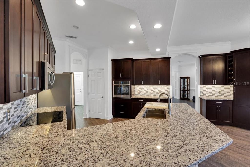 7601 226th Street East Bradenton, FL 34211 - Photo 9 of 50 a large kitchen with stainless steel appliances kitchen island granite countertop a refrigerator and stove