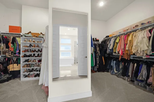a view of walk in closet with clothes and shoes