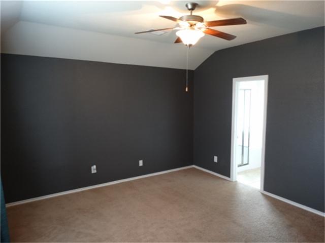 22618 Banter Point Lane Katy, TX 77449 - Photo 17 of 34 Spacious master bedroom featuring a modern ceiling fan and plush carpet, leading into a private ensuite.