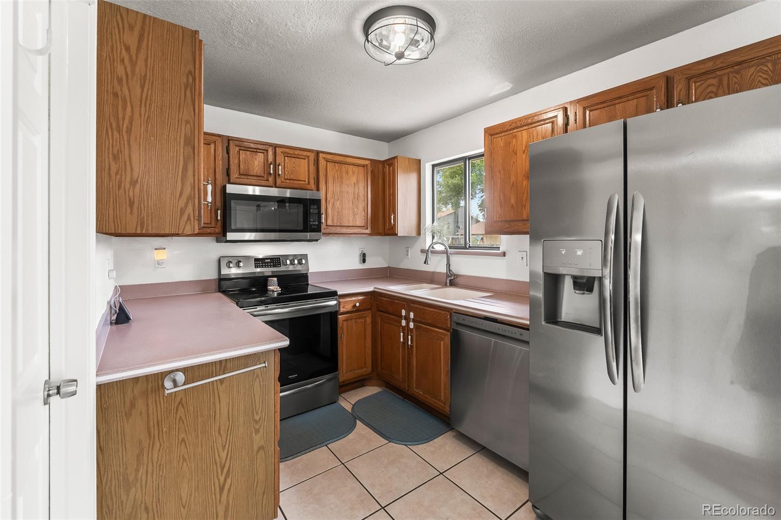 908 Trapper Drive Fort Lupton, CO 80621 - Photo 14 of 41 a kitchen with stainless steel appliances granite countertop a refrigerator stove microwave and sink