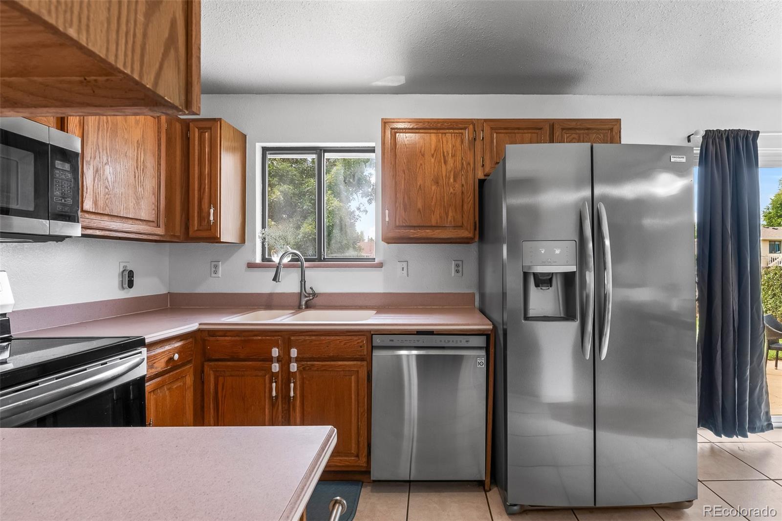 908 Trapper Drive Fort Lupton, CO 80621 - Photo 16 of 41 a kitchen with stainless steel appliances granite countertop a refrigerator a sink a stove and washer