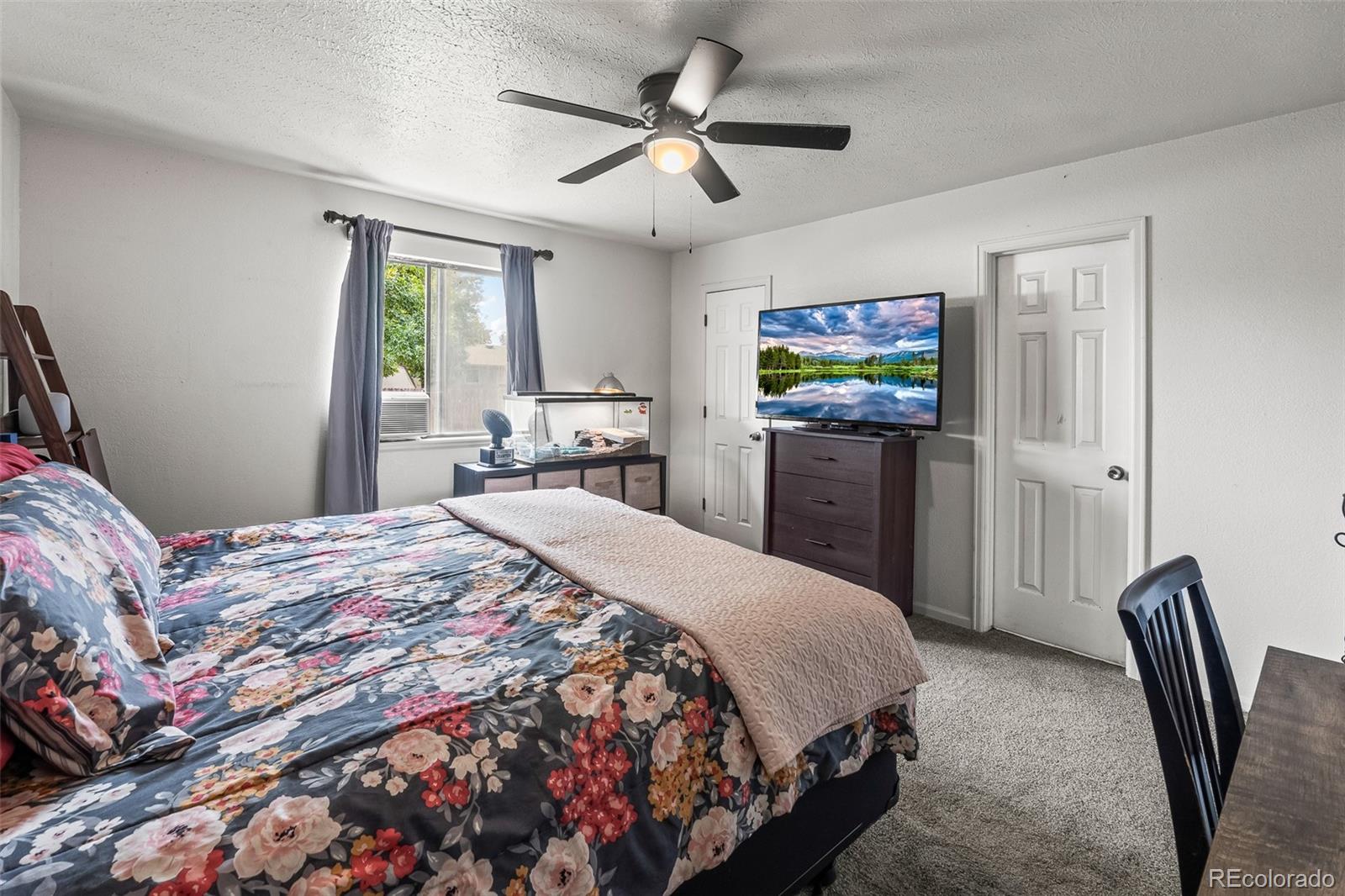 908 Trapper Drive Fort Lupton, CO 80621 - Photo 19 of 41 a bedroom with a bed and a flat screen tv