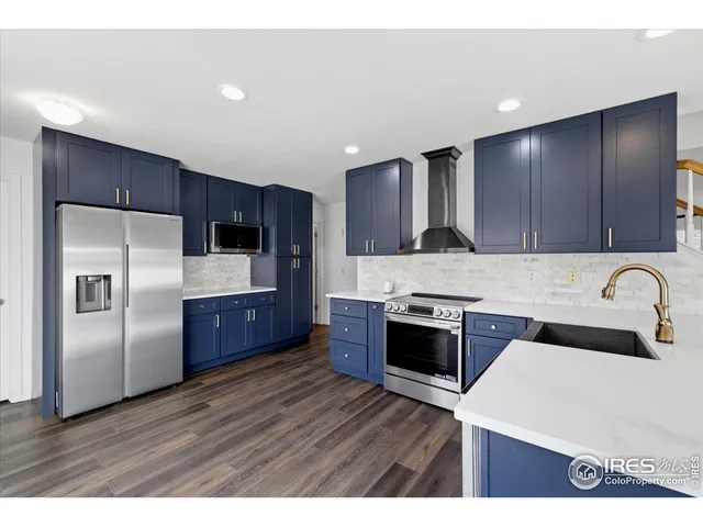 a kitchen with stainless steel appliances granite countertop a stove a sink dishwasher a refrigerator and wooden cabinets with wooden floor