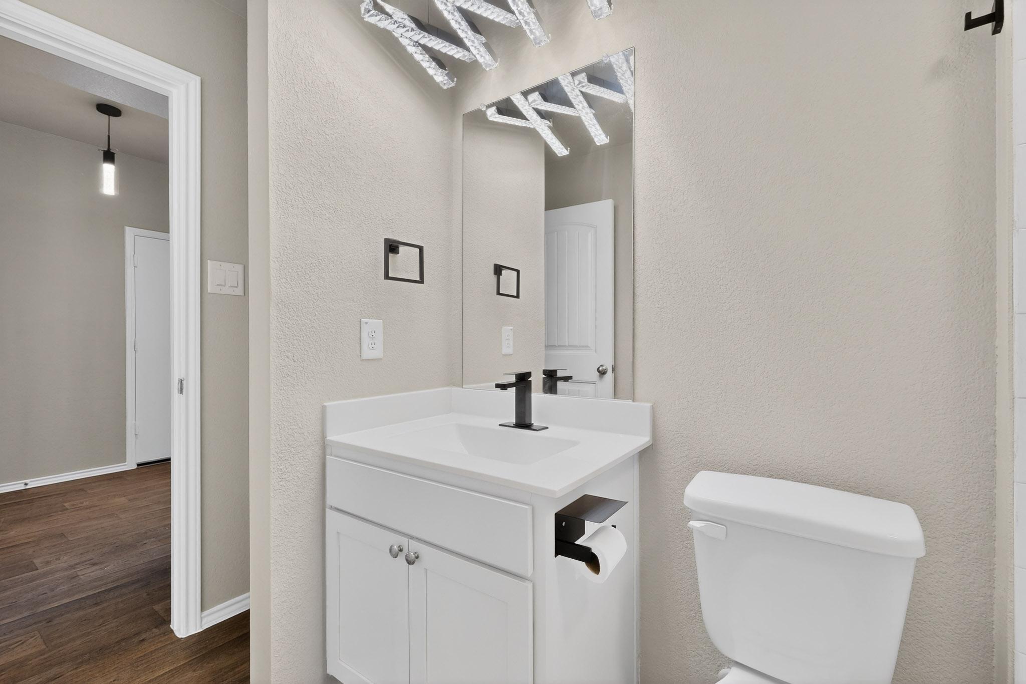 218 Sickle Loop Kyle, TX 78640 - Photo 21 of 34 Half bath featuring vanity, a textured wall, and dark wood-style flooring