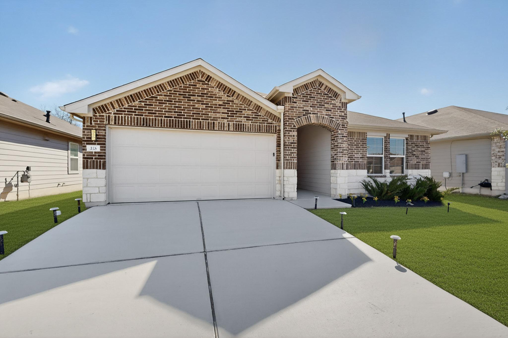 218 Sickle Loop Kyle, TX 78640 - Photo 3 of 34 View of front facade with brick siding, a front lawn, driveway, and an attached garage