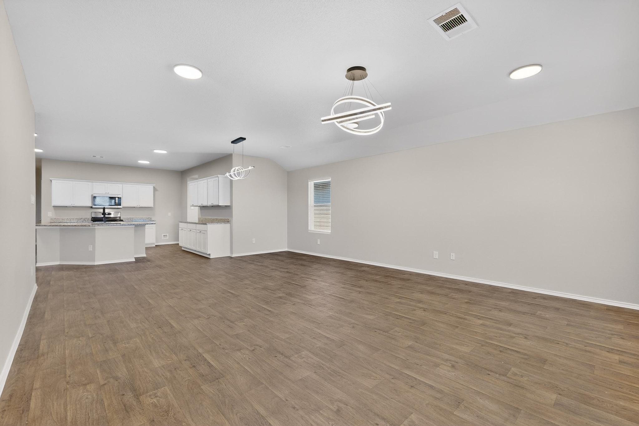218 Sickle Loop Kyle, TX 78640 - Photo 7 of 34 Unfurnished living room featuring recessed lighting, dark wood finished floors, and a chandelier