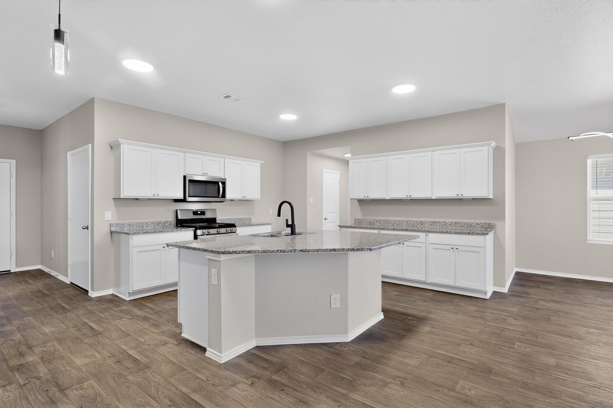 218 Sickle Loop Kyle, TX 78640 - Photo 8 of 34 Kitchen with white cabinetry, hanging light fixtures, stainless steel appliances, a kitchen island with sink, and light stone countertops
