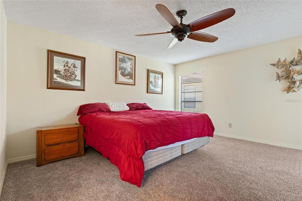 1801 East Lake Road South, Unit 4E Palm Harbor, FL 34685 - Photo 15 of 26 a spacious bedroom with a bed and a ceiling fan