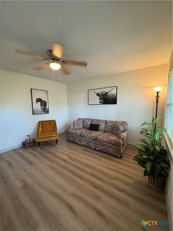 an empty room with wooden floor fan and windows