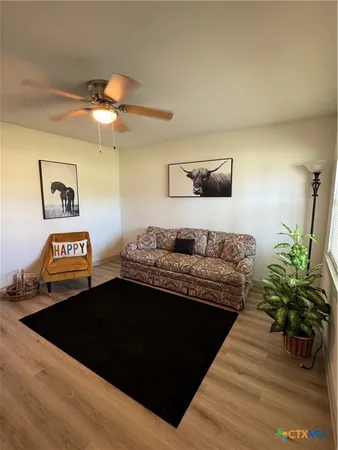 an empty room with wooden floor fan and windows
