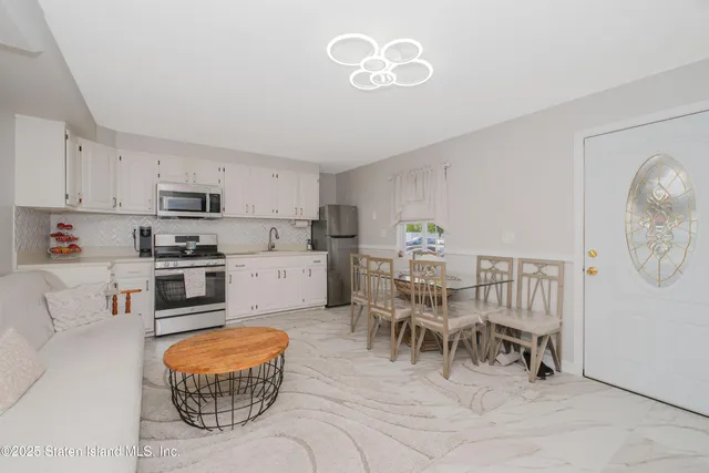 a kitchen with stainless steel appliances granite countertop a stove a refrigerator a microwave a dining table and chairs with wooden floor