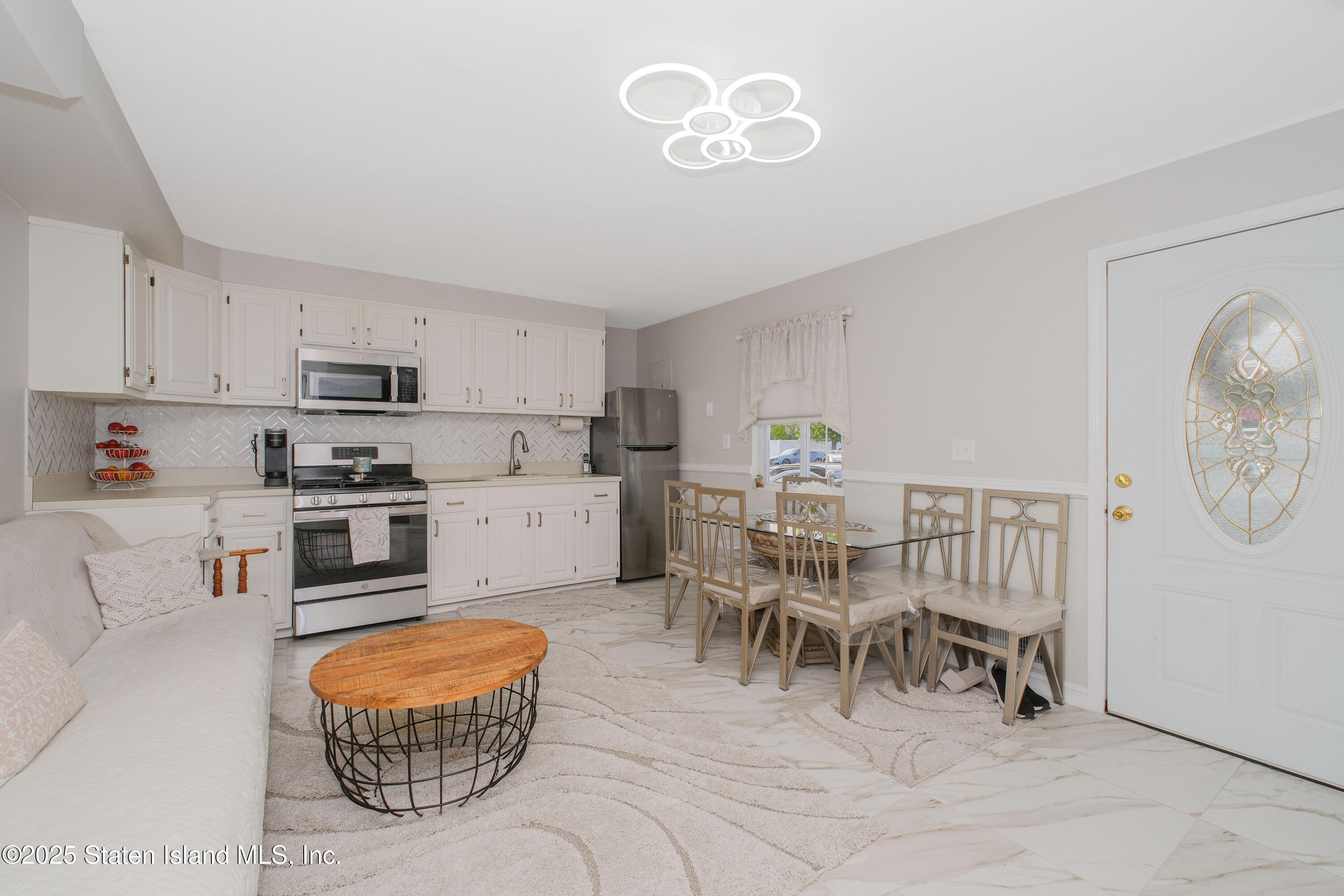 149 Crossfield Avenue Staten Island, NY 10312 - Photo 7 of 23 a kitchen with stainless steel appliances granite countertop a stove a refrigerator a microwave a dining table and chairs with wooden floor