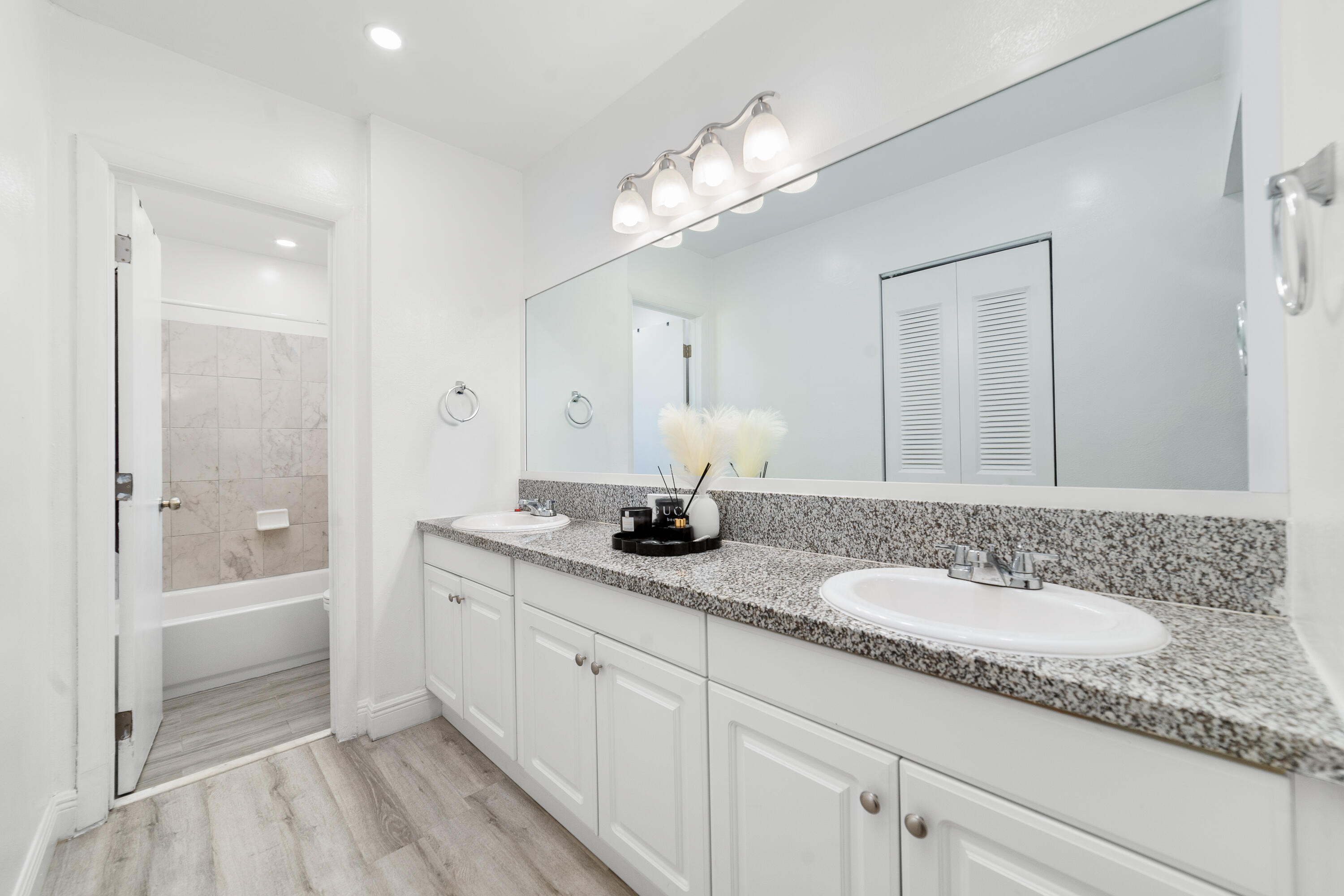 2710 Riverside Drive, Unit 201A Coral Springs, FL 33065 - Photo 15 of 23 a bathroom with a granite countertop double vanity sink a mirror and a bathtub