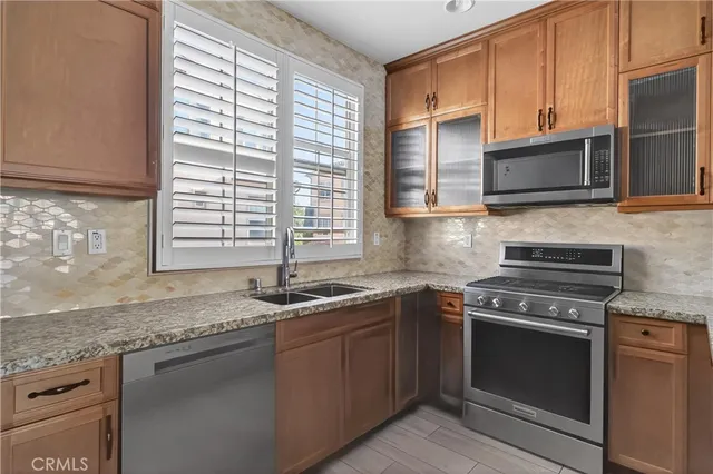 a kitchen with granite countertop stainless steel appliances a sink stove and cabinets