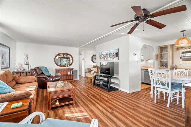 a living room with furniture a wooden floor and a ceiling fan