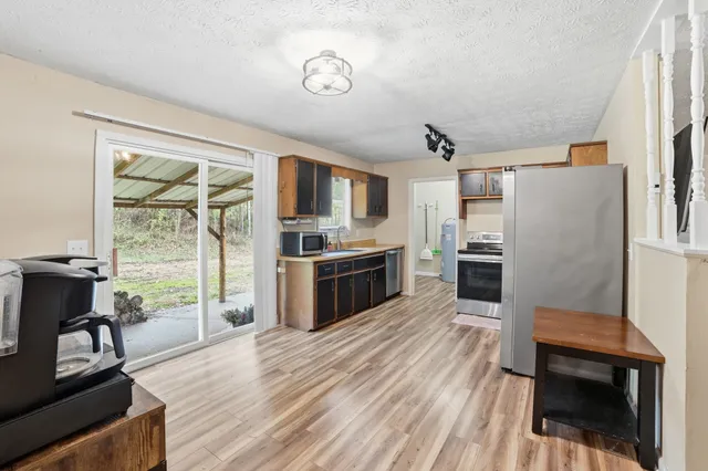 a kitchen with granite countertop a refrigerator a stove a sink and a dining table with wooden floor