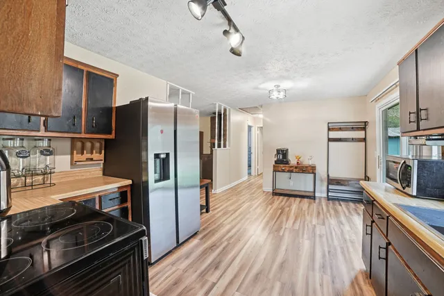 a kitchen with stainless steel appliances a stove refrigerator and chairs