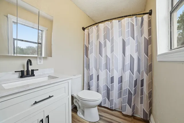 a bathroom with a granite countertop sink a toilet and a mirror