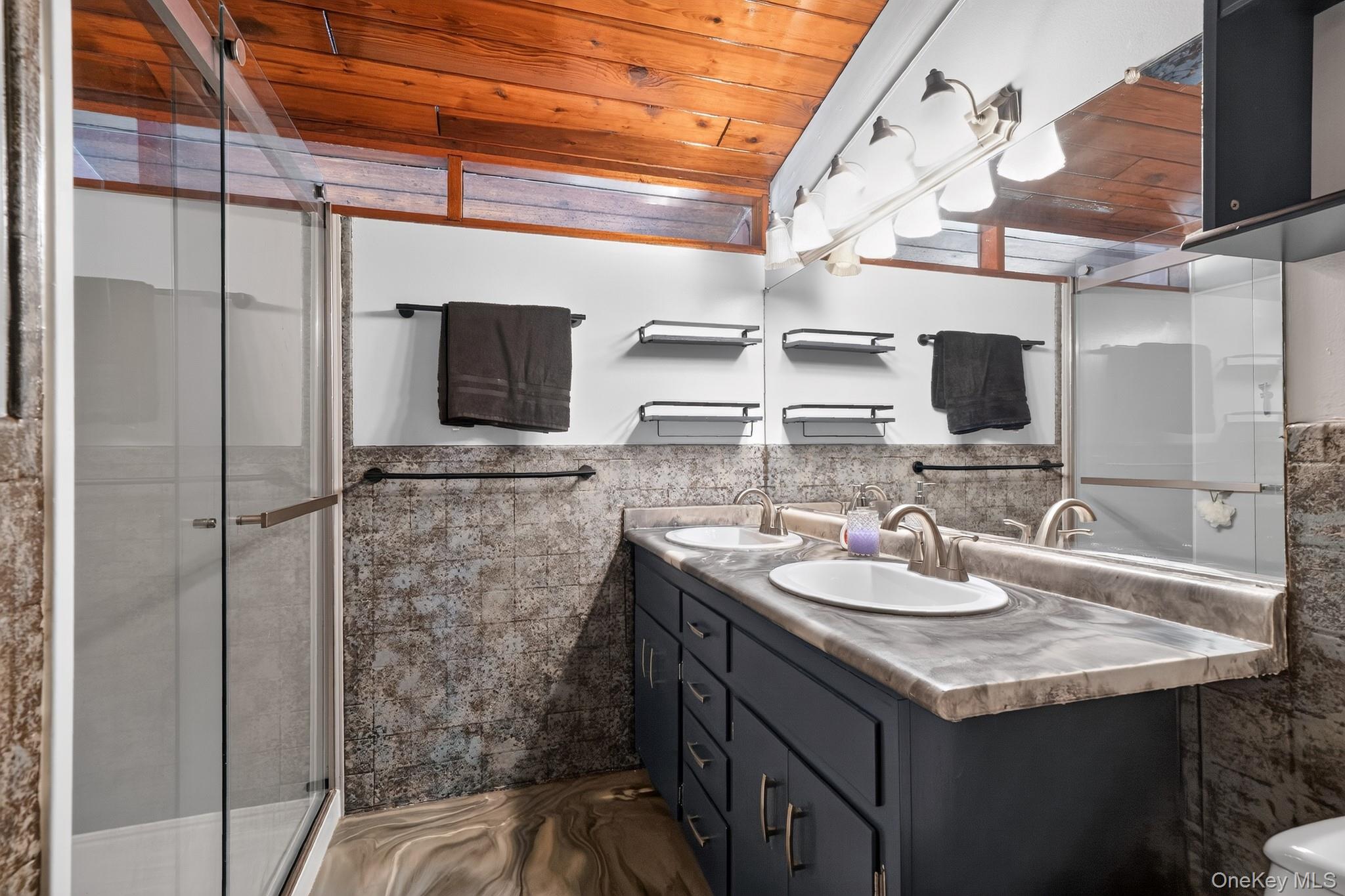 424 Laroe Road Chester, NY 10918 - Photo 4 of 43 Bathroom featuring a dual-sink vanity with gray cabinetry and matching countertop, a glass-enclosed shower, a wood-finish ceiling, and textured wall accents