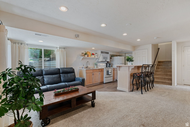 14883 Tooele Lane Draper, UT 84020 - Photo 34 of 49 Lower level living space featuring recessed lighting, a full kitchen with light wood cabinetry, a breakfast bar with seating, and a window providing natural light