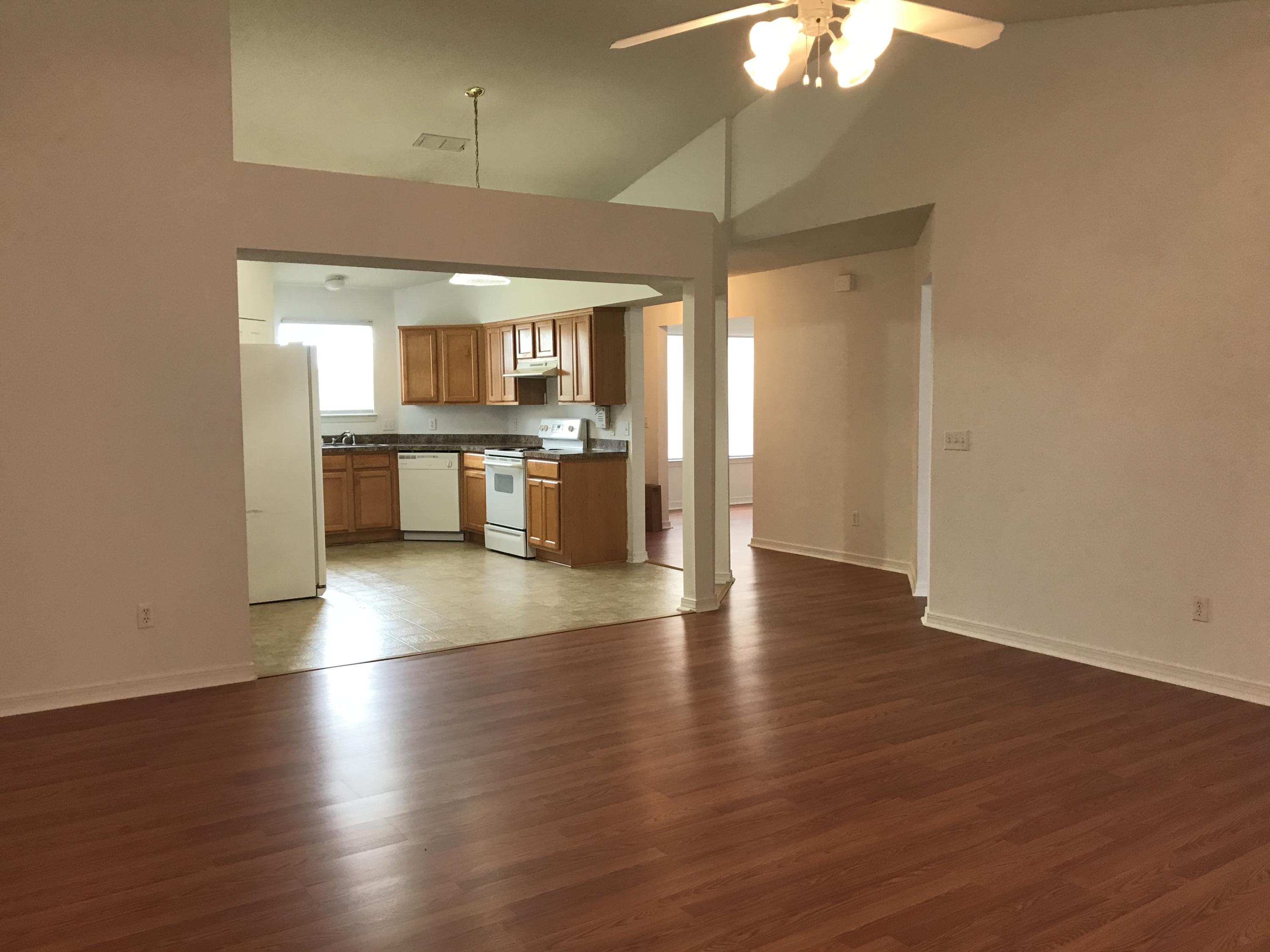 294 Limestone Circle Crestview, FL 32539 - Photo 6 of 19 an empty room with wooden floor a ceiling fan and kitchen view