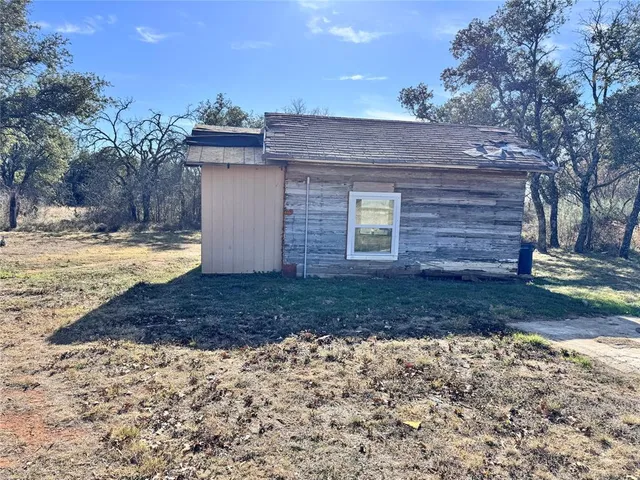 a backyard of a house with a tree and wooden fence