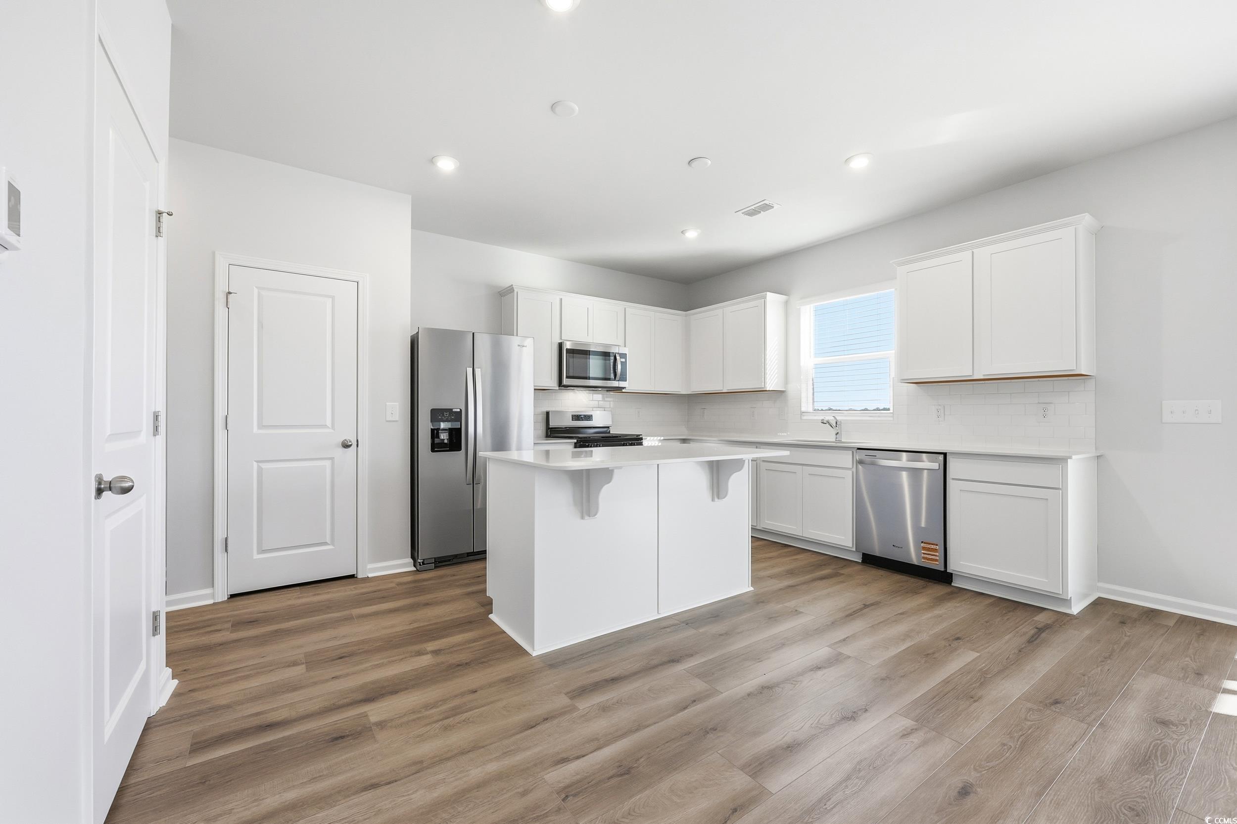 3055 Visionary Drive Myrtle Beach, SC 29588 - Photo 12 of 31 Kitchen with white cabinetry, appliances with stainless steel finishes, decorative backsplash, and a center island