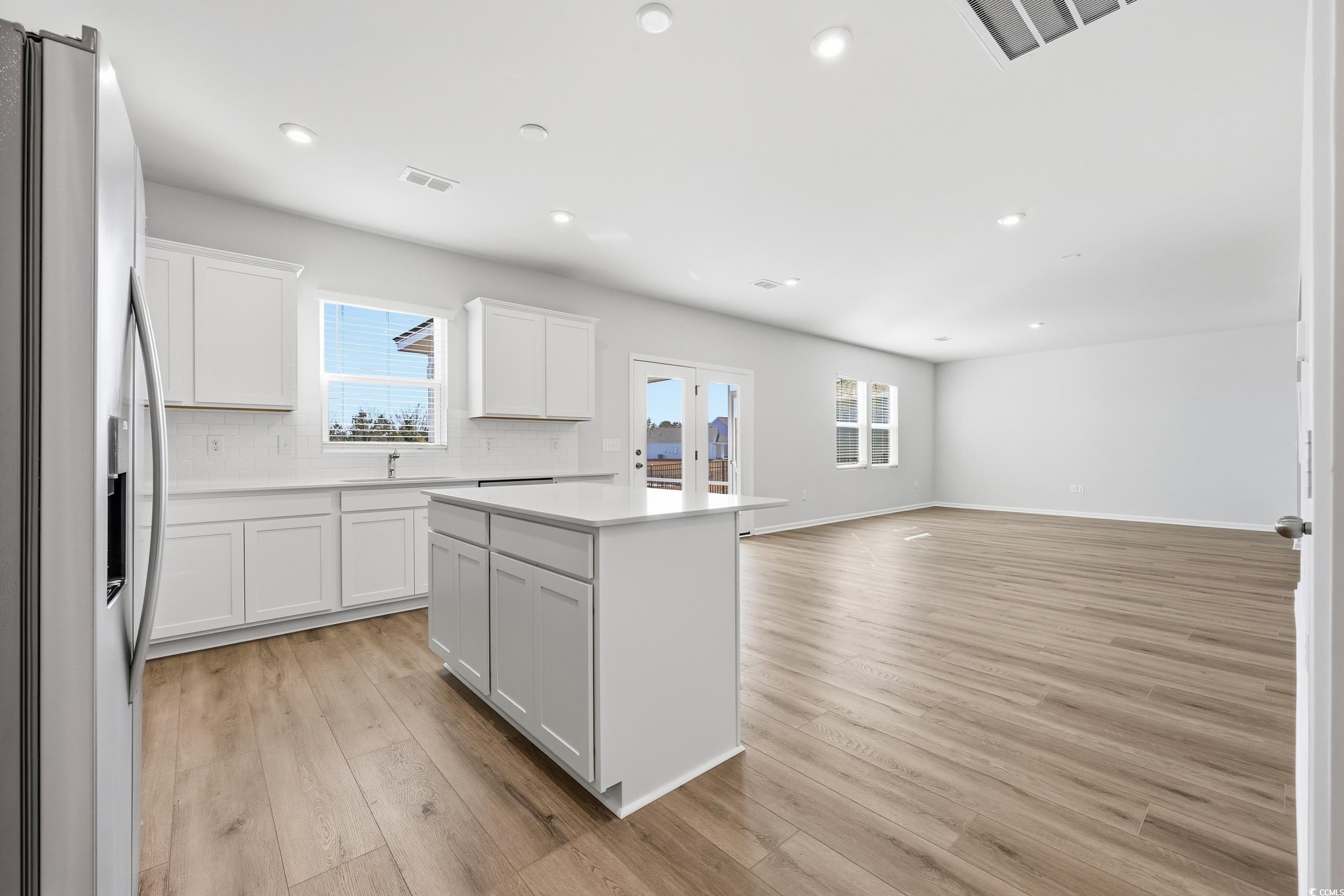 3055 Visionary Drive Myrtle Beach, SC 29588 - Photo 14 of 31 Kitchen with stainless steel fridge, white cabinetry, a kitchen island, plenty of natural light, and recessed lighting