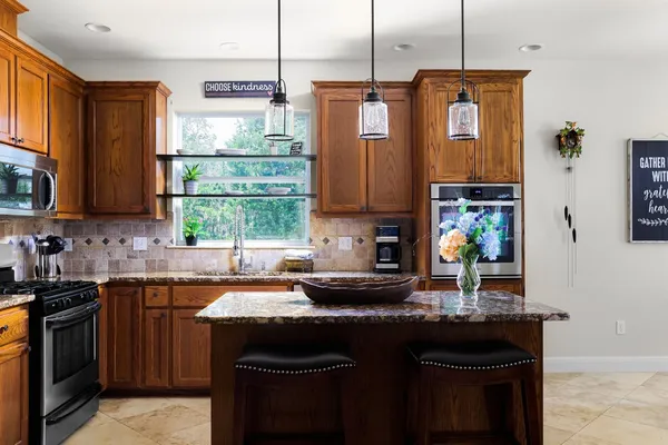 a kitchen with stainless steel appliances granite countertop a sink a stove a microwave a sink a refrigerator and cabinets