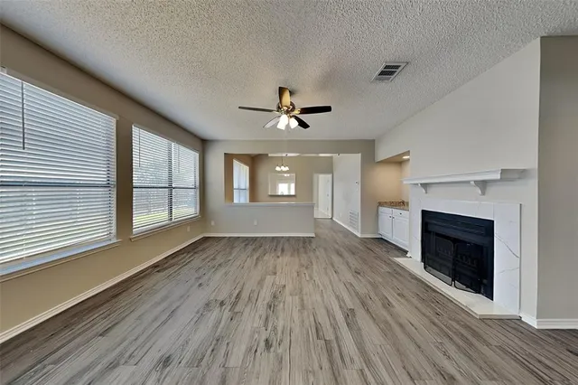 an empty room with wooden floor fireplace and windows