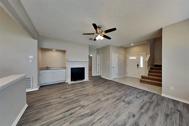 a view of a livingroom with a fireplace a ceiling fan and wooden floor