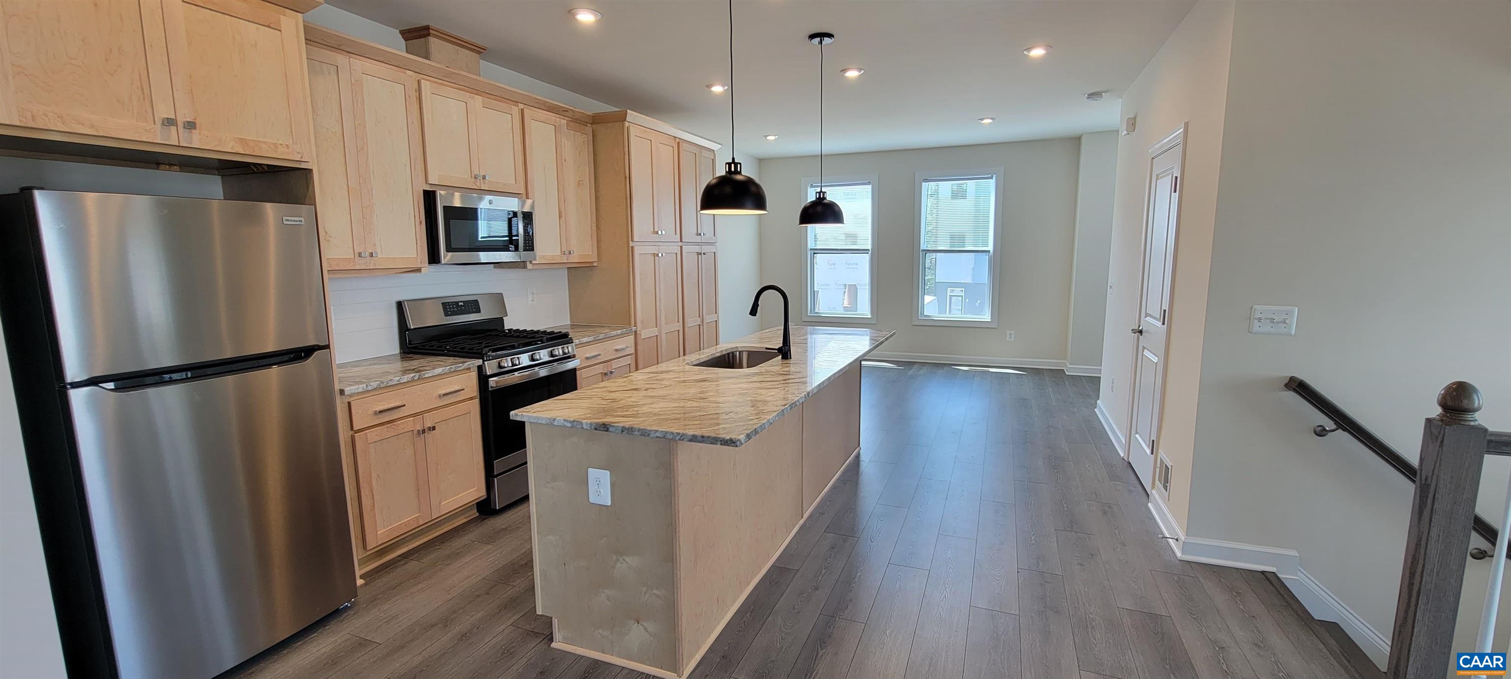 a kitchen with refrigerator a sink and wooden floor