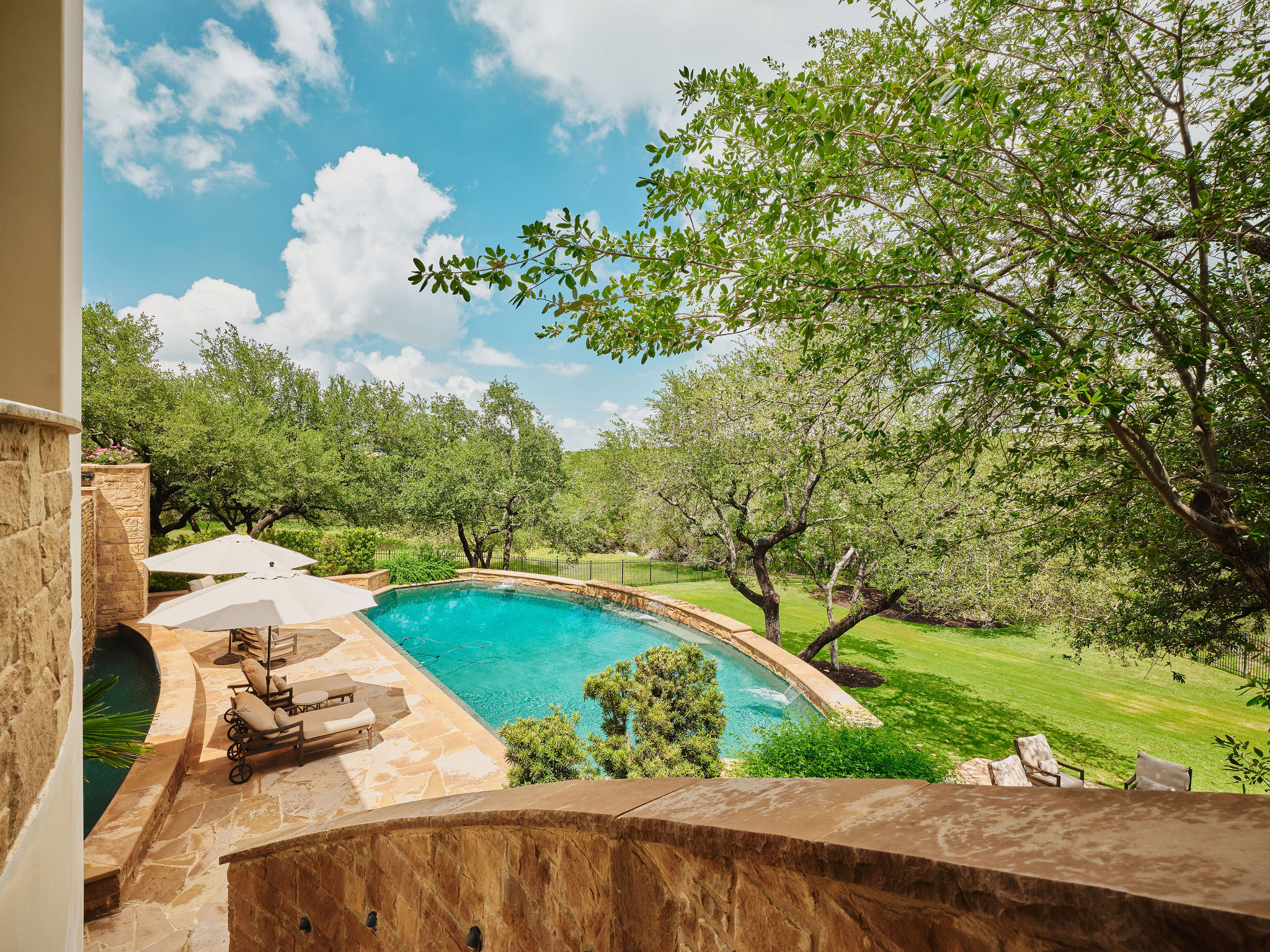 433 Brandon Way Austin, TX 78733 - Photo 27 of 40 A private swimming pool with flagstone decking is set amidst mature trees and verdant landscaping, offering a serene outdoor retreat.