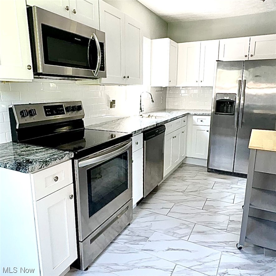 1055 Hillstone Road Cleveland Heights, OH 44121 - Photo 4 of 16 Kitchen featuring appliances with stainless steel finishes, backsplash, light tile flooring, and white cabinets