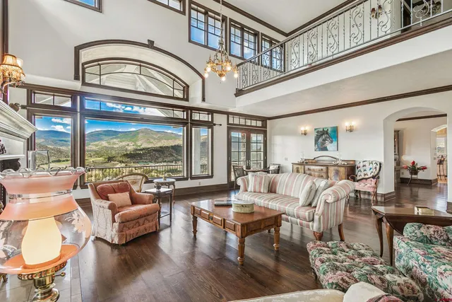 a living room with furniture a rug a large window and a chandelier