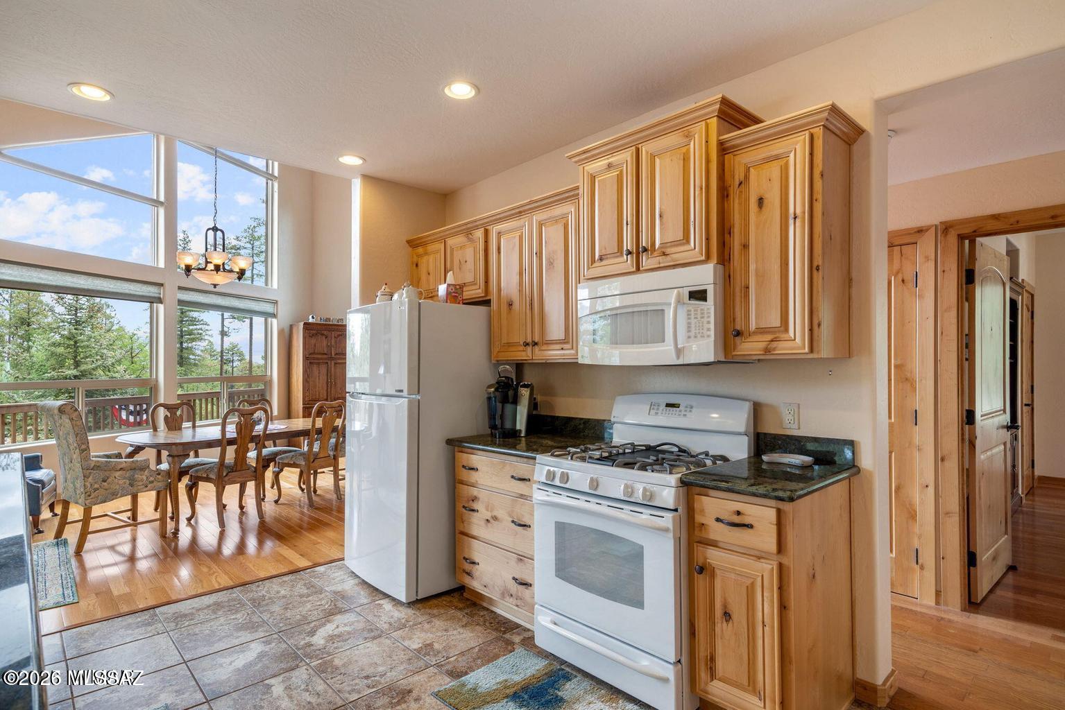 17 2195 Alpine, AZ 85920 - Photo 3 of 48 a kitchen with granite countertop a refrigerator a stove a sink a dining table and chairs with wooden floor