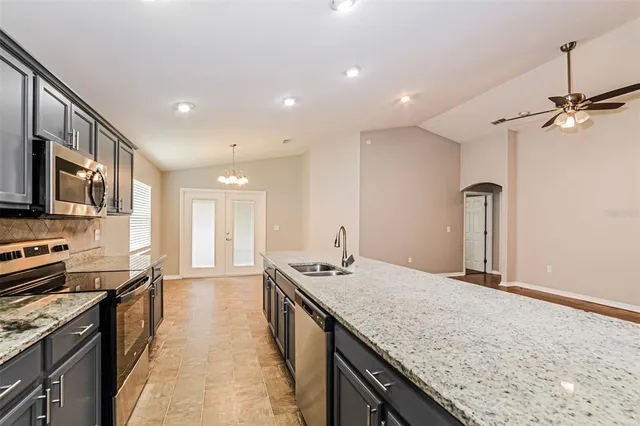 a kitchen with stainless steel appliances granite countertop a sink a stove and a wooden cabinets