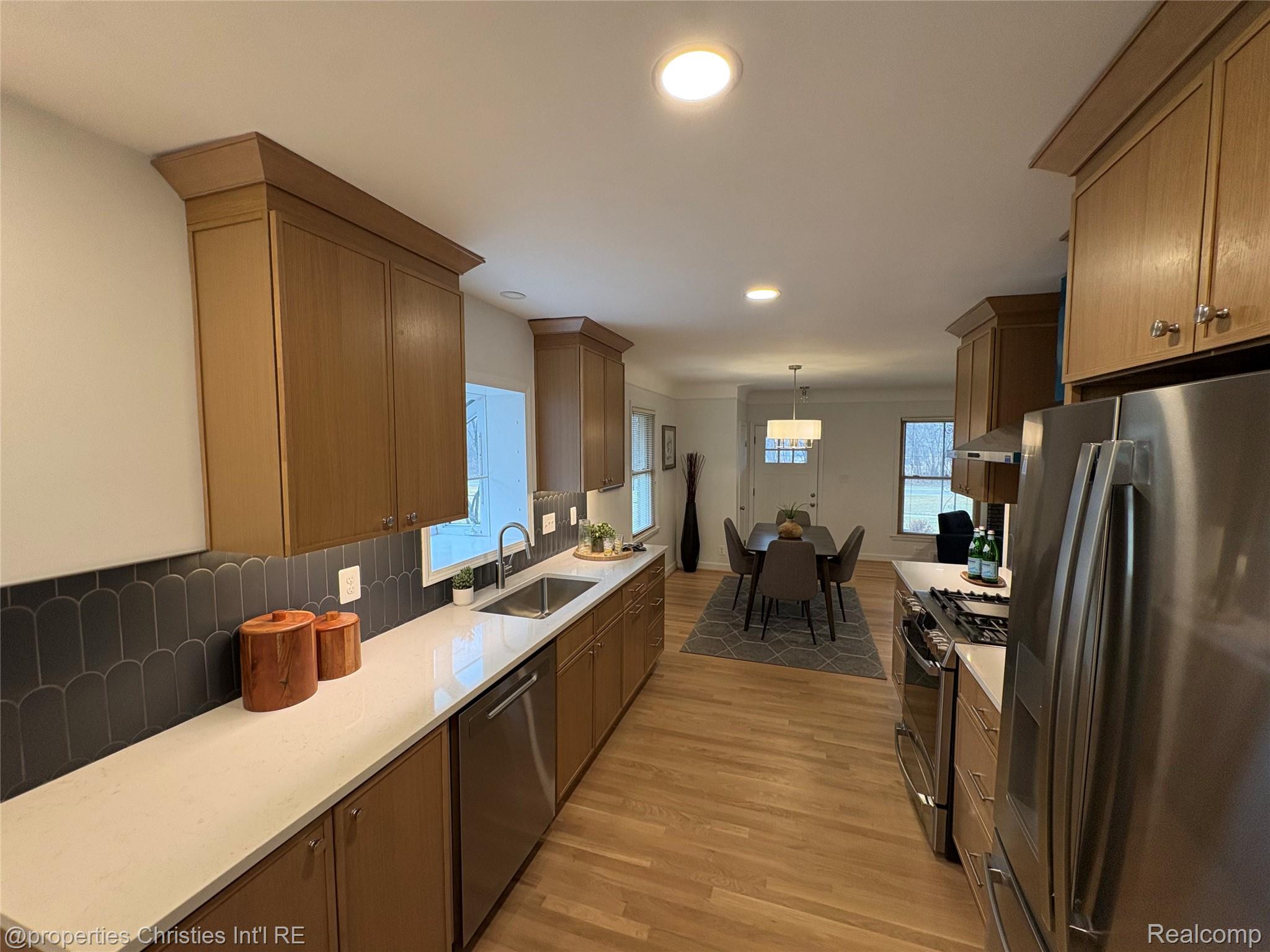 17330 Beverly Road Franklin, MI 48025 - Photo 8 of 24 Kitchen featuring stainless steel appliances, light wood-style floors, tasteful backsplash, and light stone counters