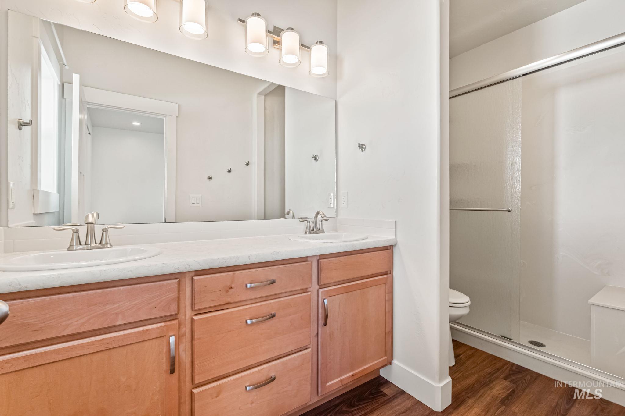 395 Cutlass Payette, ID 83661 - Photo 15 of 26 Bathroom with a stall shower, double vanity, and dark wood-type flooring