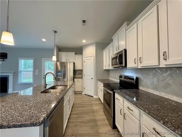 a kitchen with stainless steel appliances granite countertop a stove top oven a sink and dishwasher