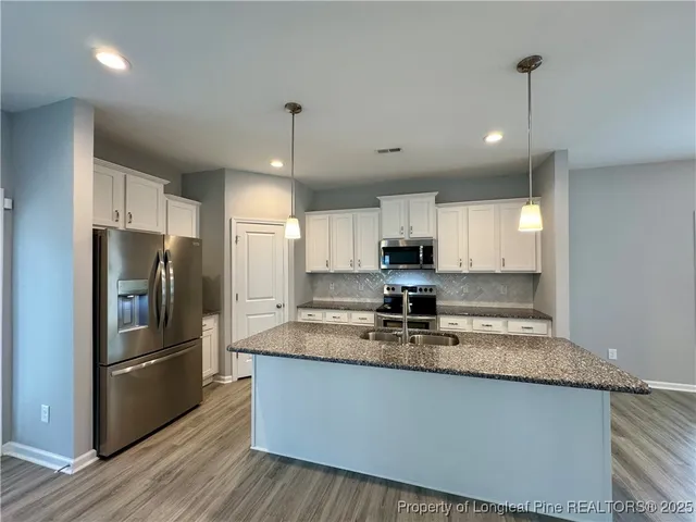 a kitchen with kitchen island a counter space a refrigerator and cabinets