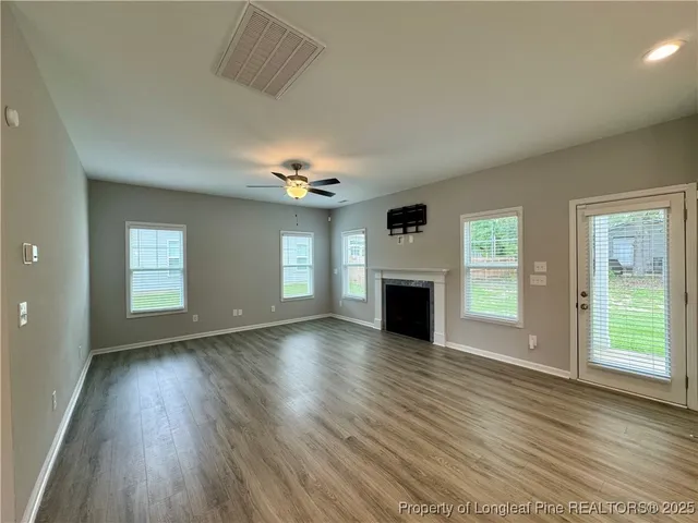 an empty room with wooden floor fireplace and windows