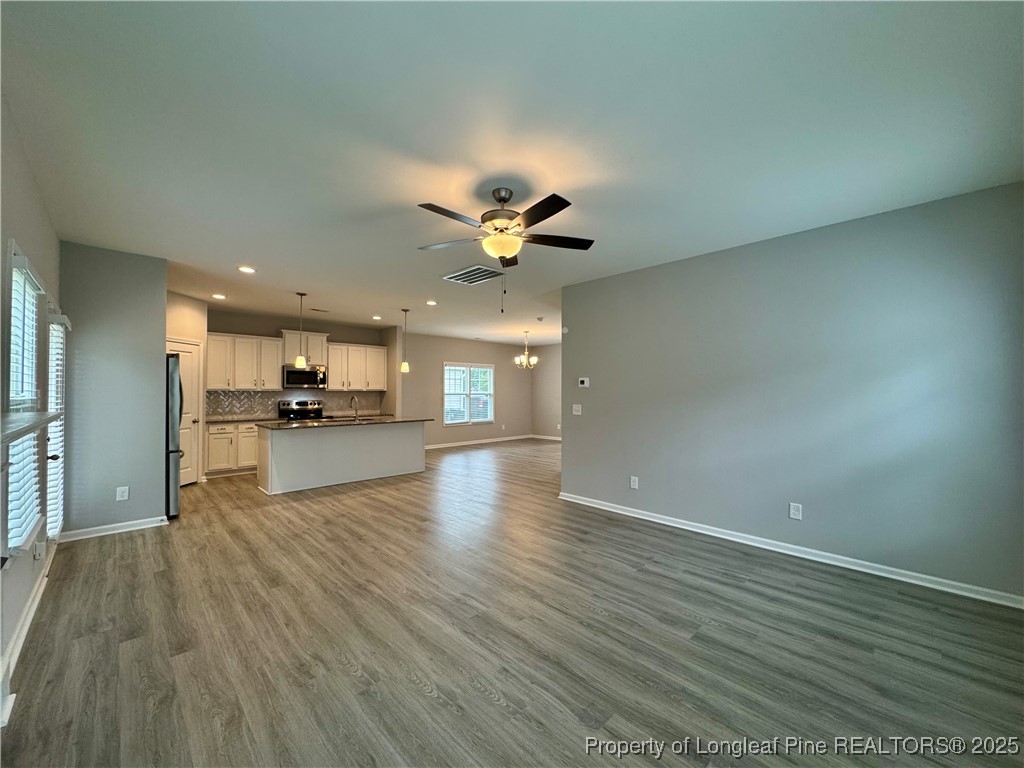 808 Jackson Street Raeford, NC 28376 - Photo 8 of 21 a view of an empty room with wooden floor and a kitchen
