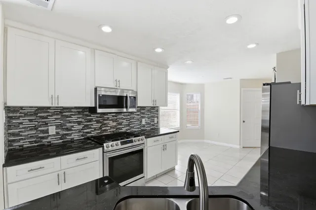 a kitchen with granite countertop white cabinets and stainless steel appliances