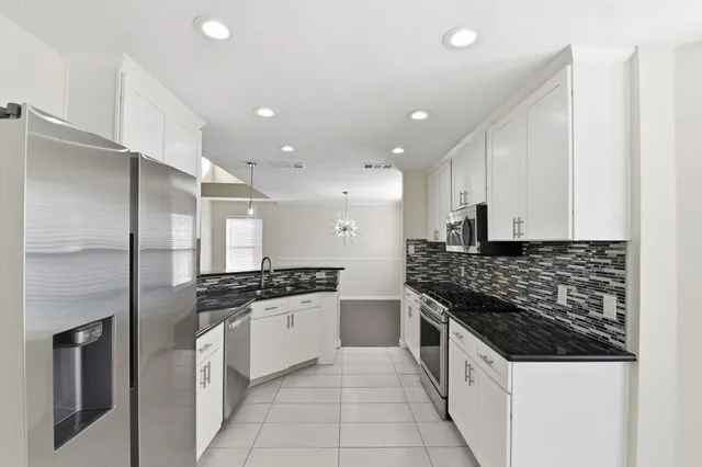 a large kitchen with stainless steel appliances granite countertop a stove and a refrigerator