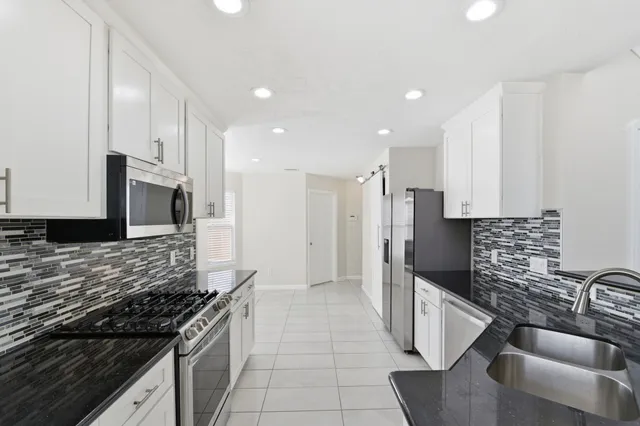a kitchen with stainless steel appliances granite countertop a sink stove and refrigerator