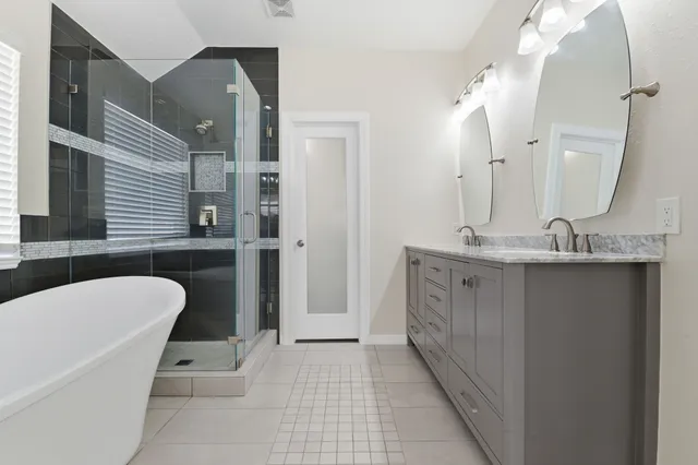 a bathroom with a double vanity sink a toilet a mirror and shower