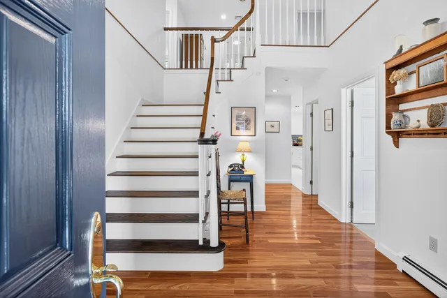 a kitchen with kitchen island a stove a sink and white cabinets with wooden floors
